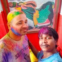 young men playing with colours on Holi with painting behind