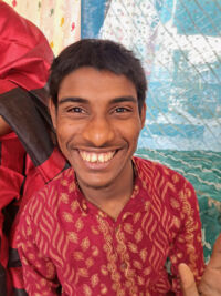 young man smiling wearing red printed shirt