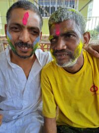 two men with bright pink powder mark on their foreheads