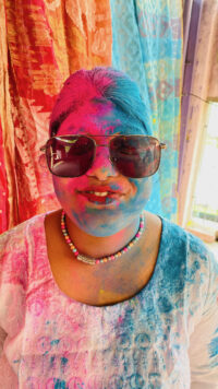 girl in sunglasses with coloured powder on her face and hair
