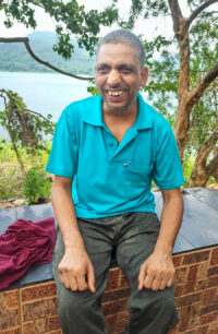 Older man in aqua blue shirt smiling widely