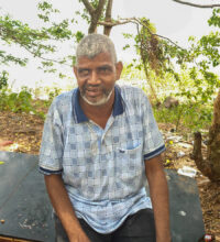 Older man with white short hair and beard smiling